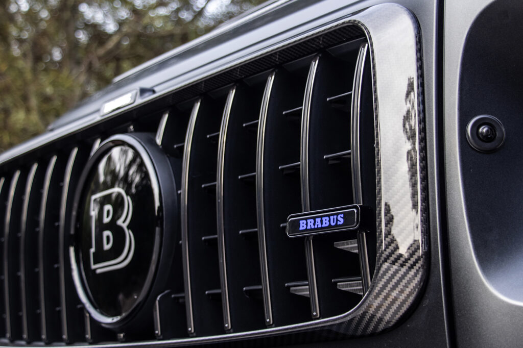 Rear view of the BRABUS Widestar G63 showcasing the exposed carbon fiber spare wheel cover, aerodynamic roof spoiler, and the Active Sport Exhaust system.